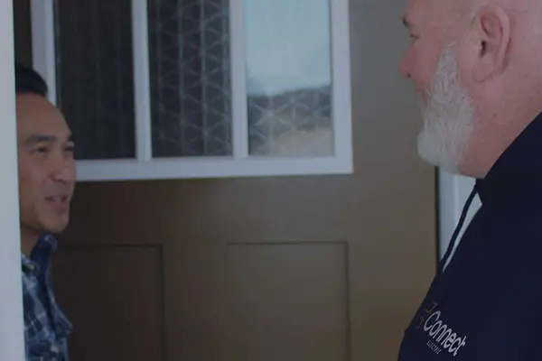 A professional Connect Electric technician in conversation with a homeowner outside of their home.